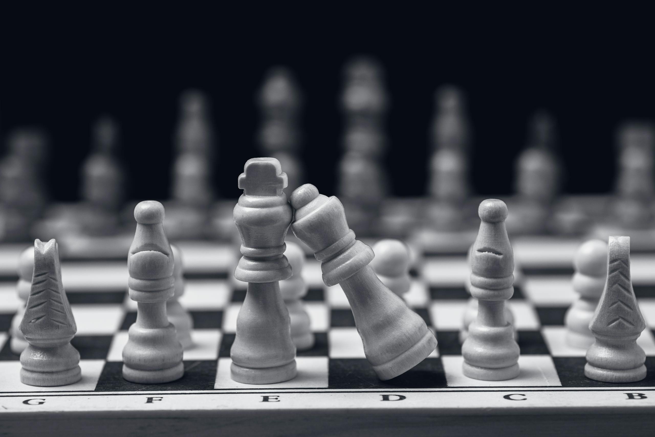 Close-up of chess pieces on a board, emphasizing strategic play with a leaning king.