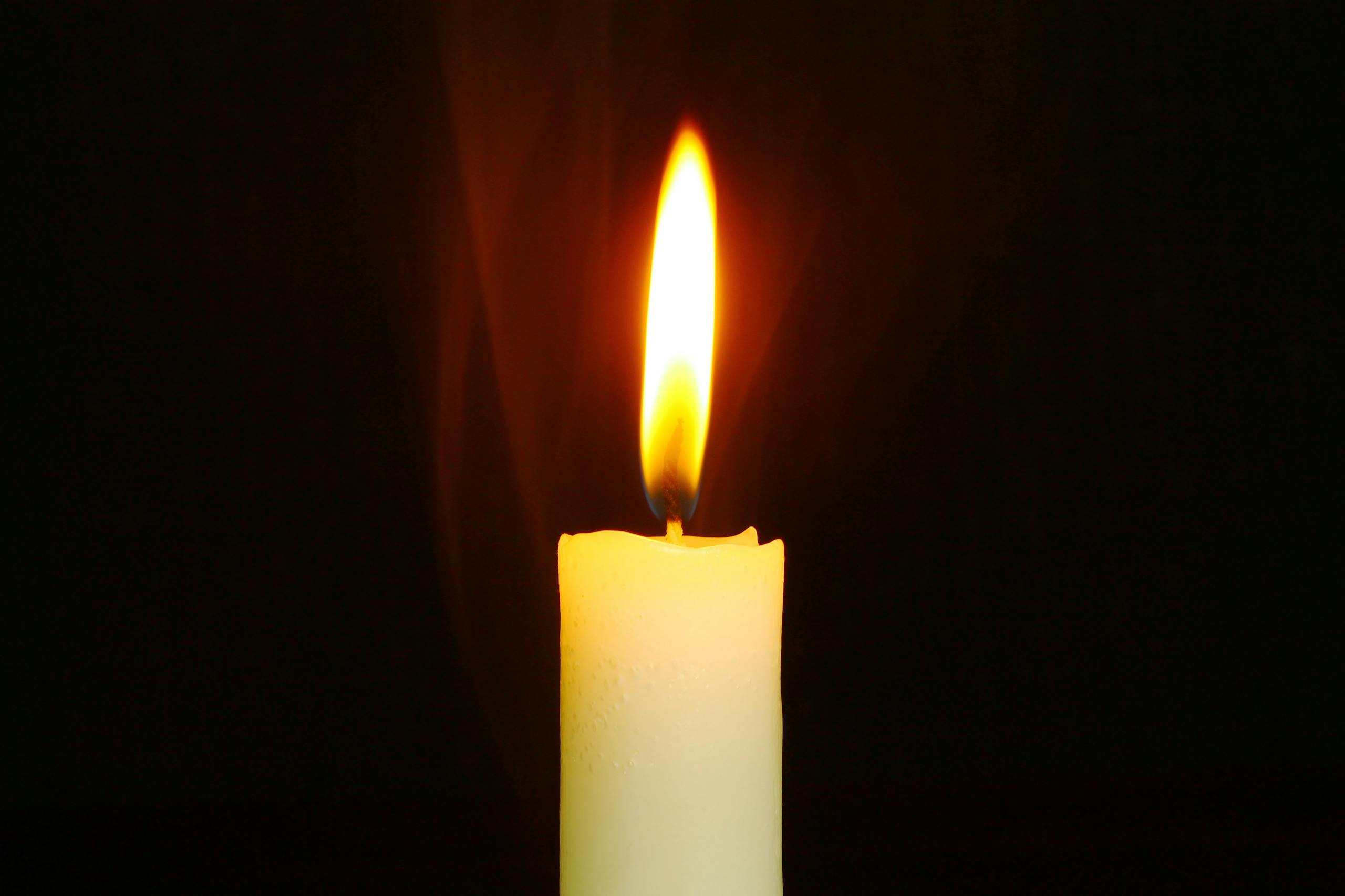 A single candle burning brightly in the dark, symbolizing light and hope.